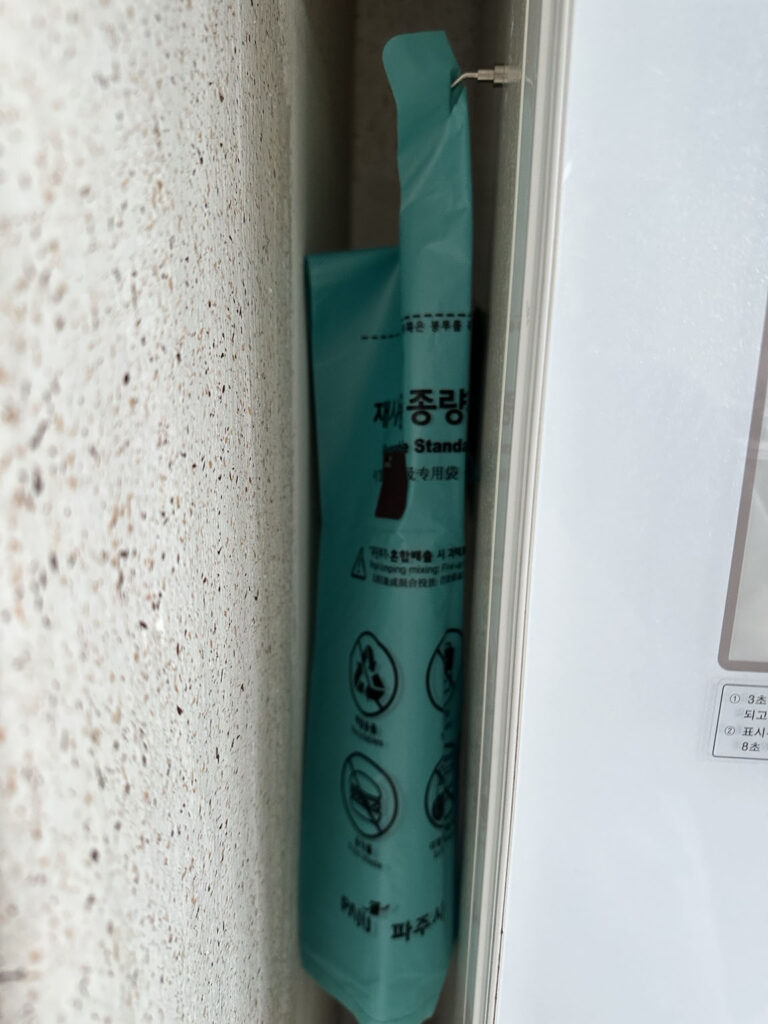 냉장고 옆 좁은 틈에 종량제봉투를 걸어둔 모습