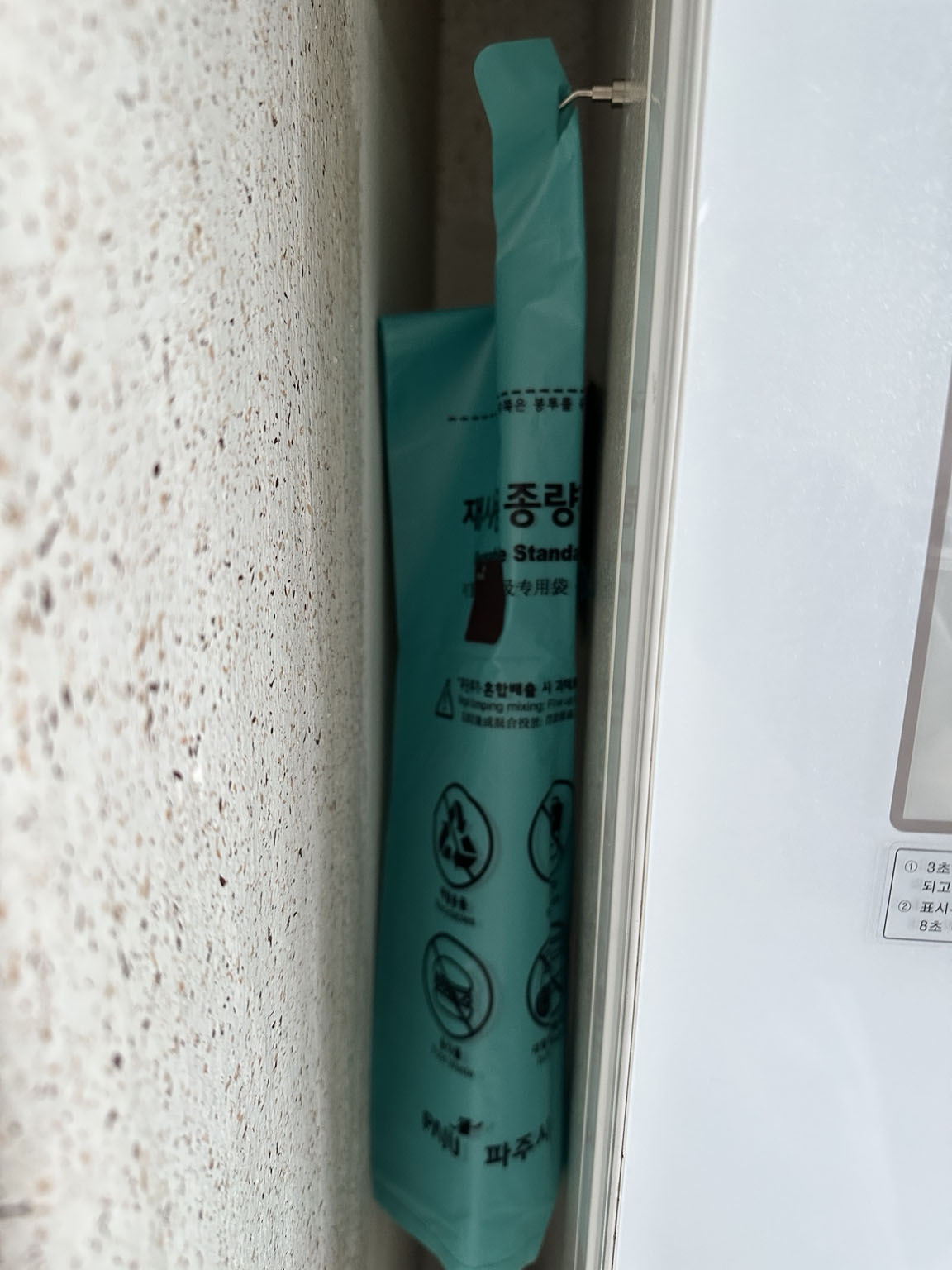 냉장고 옆 좁은 틈에 종량제봉투를 걸어둔 모습